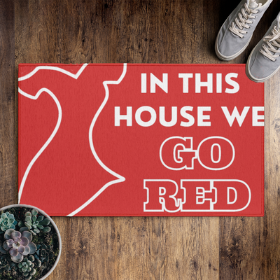 Red doormat that says "In this house  we go red" with a large red dress icon.