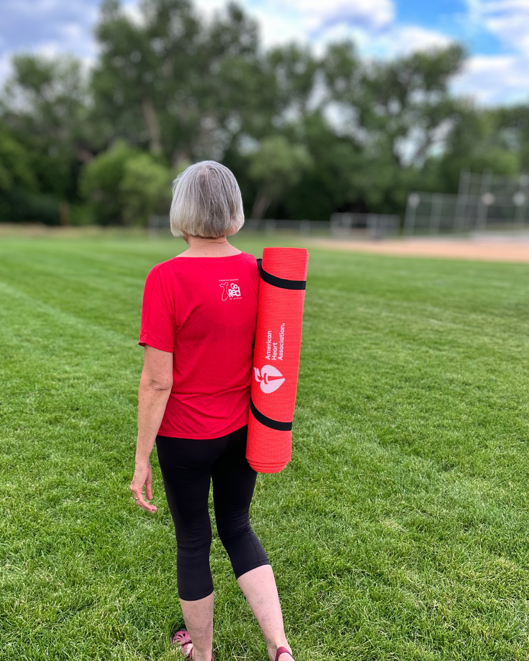 Image showing a woman walking carrying yoga matt over her shoulder.