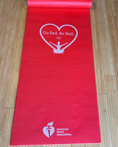 Picture showing unrolled yoga mat with Go Red. Be Well Logo and AHA logo on red mat.